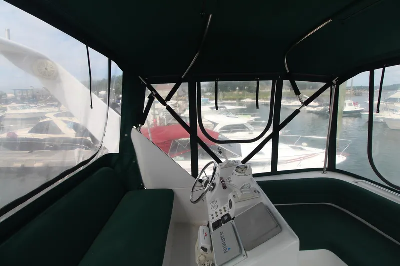 Slide: The Image of 1999 Mainship 31 Sedan Bridge helm with marina view, featuring green seating and navigation controls. - 8