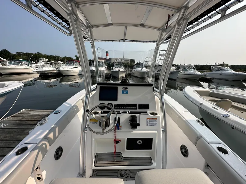 Slide: The Image of 2023 Sea Fox 228 Commander boat interior at marina, featuring steering console and docked boats. - 10