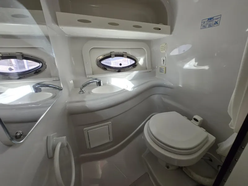 Slide: The Image of 2006 Crownline 255 CCR boat bathroom with sink, toilet, and porthole window. - 16