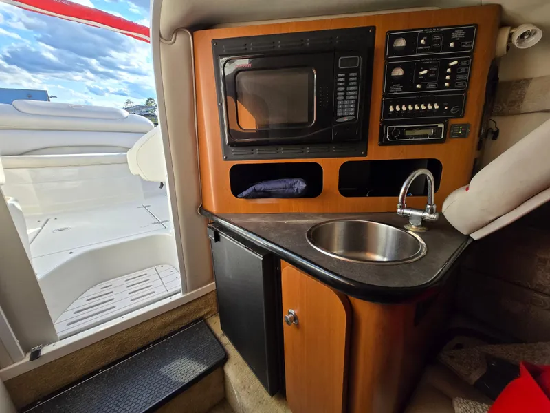 Slide: The Image of 2006 Crownline 255 CCR boat interior with kitchenette, featuring a microwave and sink. - 19
