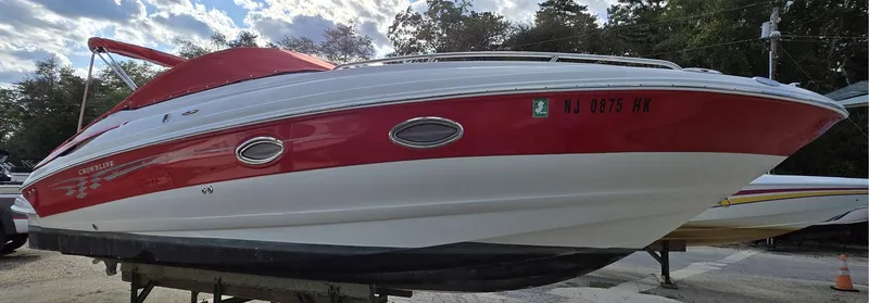 Slide: The Image of 2006 Crownline 255 CCR boat with red and white exterior, docked outdoors. - 23