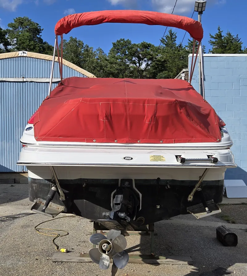 Slide: The Image of 2006 Crownline 255 CCR boat with red canopy and cover, parked outdoors. - 26