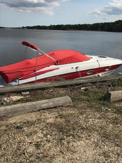 Slide: The Image of 2006 Crownline 255 CCR boat with red cover by a serene lake. - 31