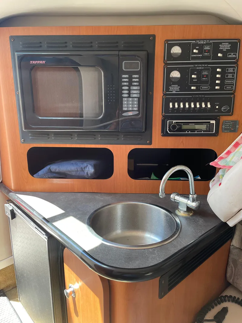 Slide: The Image of 2006 Crownline 255 CCR boat interior with microwave, control panel, sink, and storage compartments. - 8