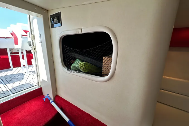 Slide: The Image of Interior of 2004 Hustler 388 SLINGSHOT boat with storage compartment and red carpet. - 24