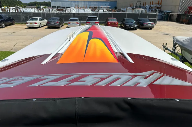 Slide: The Image of 2004 Hustler 388 SLINGSHOT boat with vibrant red and orange design, parked outdoors. - 26