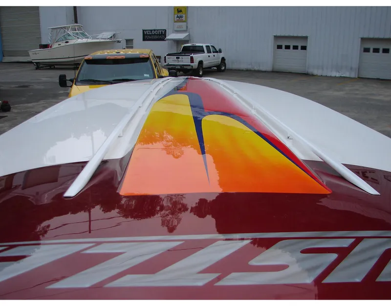 Slide: The Image of 2004 Hustler 388 SLINGSHOT boat with vibrant red and yellow design in a marina. - 7