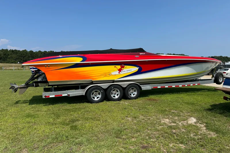 Slide: The Image of 2004 Hustler 388 SLINGSHOT speedboat with vibrant red and yellow design on a trailer. - 9