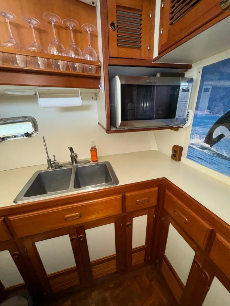 Slide: The Image of 1987 Kadey-Krogen Silhouette kitchen with wooden cabinets, double sink, microwave, and glass rack. - 10
