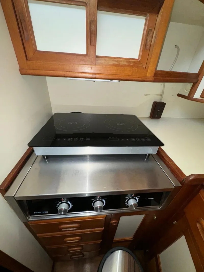 Slide: The Image of 1987 Kadey-Krogen Silhouette kitchen with modern stovetop and wooden cabinetry. - 12