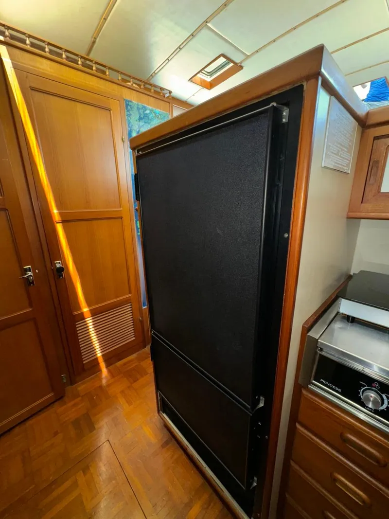 Slide: The Image of 1987 Kadey-Krogen Silhouette interior with wooden cabinetry and black refrigerator. - 13