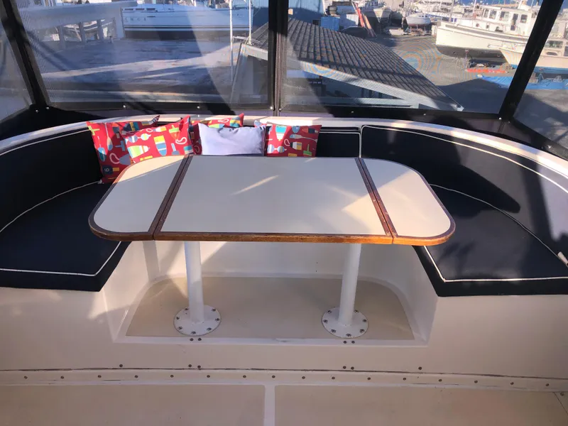 Slide: The Image of 1987 Kadey-Krogen Silhouette boat interior with cushioned seating and table, featuring colorful pillows. - 33