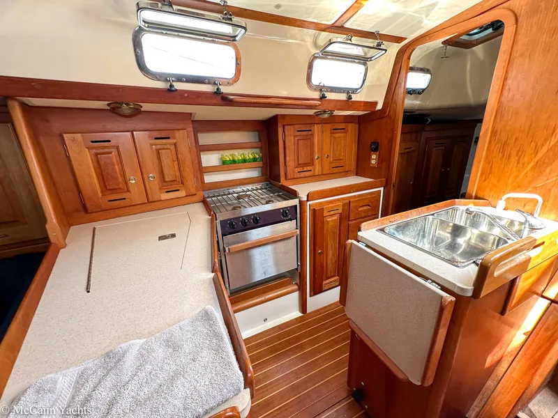 Slide: The Image of Cozy 2002 Tartan 3700 yacht interior with wooden cabinetry and compact kitchen. - 19