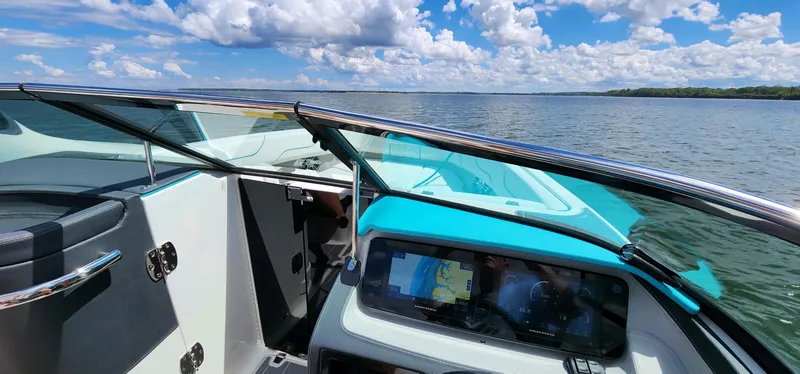 Slide: The Image of 2023 Regal LS6 boat interior with navigation system, overlooking a serene lake under a blue sky. - 10