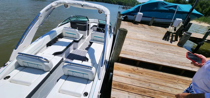 Slide: The Image of 2023 Regal LS6 boat docked by a wooden pier on a sunny day. - 11