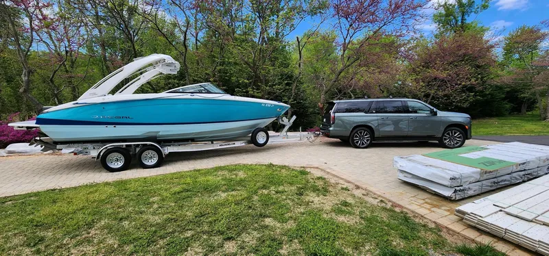 Slide: The Image of 2023 Regal LS6 boat on trailer, parked beside a large SUV in a driveway. - 3