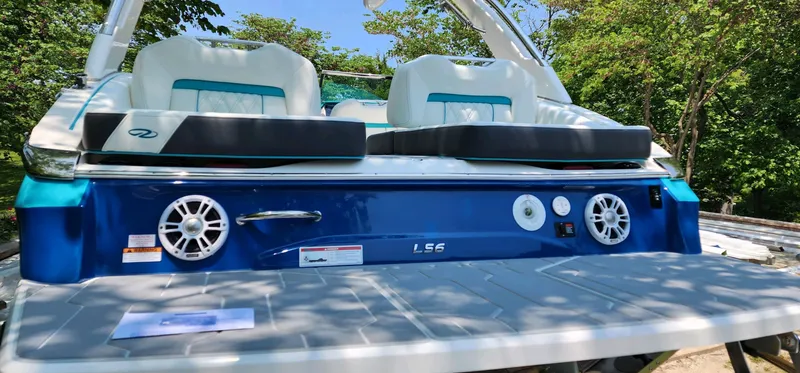 Slide: The Image of 2023 Regal LS6 boat with sleek seating and modern audio system, set against a lush green backdrop. - 5