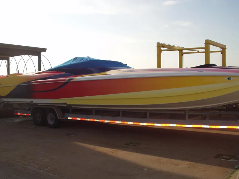 The Image of 2003 Hustler 377 Talon speedboat with vibrant red and yellow design on trailer. - 1