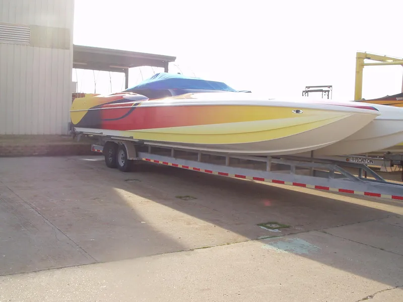 Slide: The Image of 2003 Hustler 377 Talon speedboat with vibrant yellow and red design on a trailer. - 3