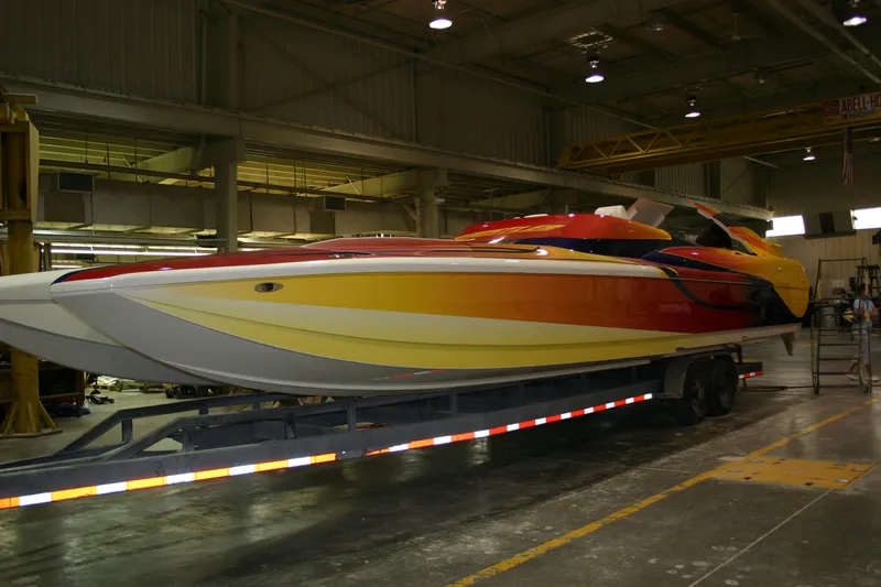 Slide: The Image of 2003 Hustler 377 Talon speedboat with vibrant red and yellow design on a trailer in a warehouse. - 4