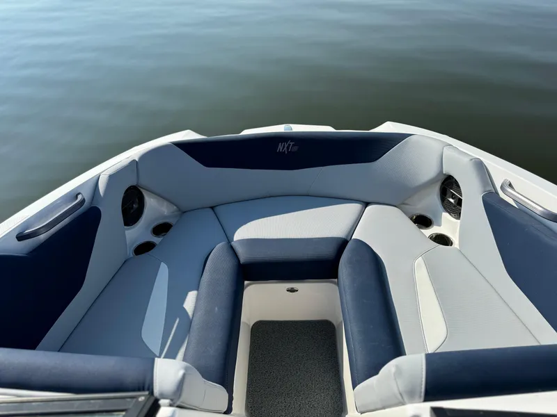Slide: The Image of 2022 MasterCraft NXT20 boat interior with cushioned seating on calm water. - 11