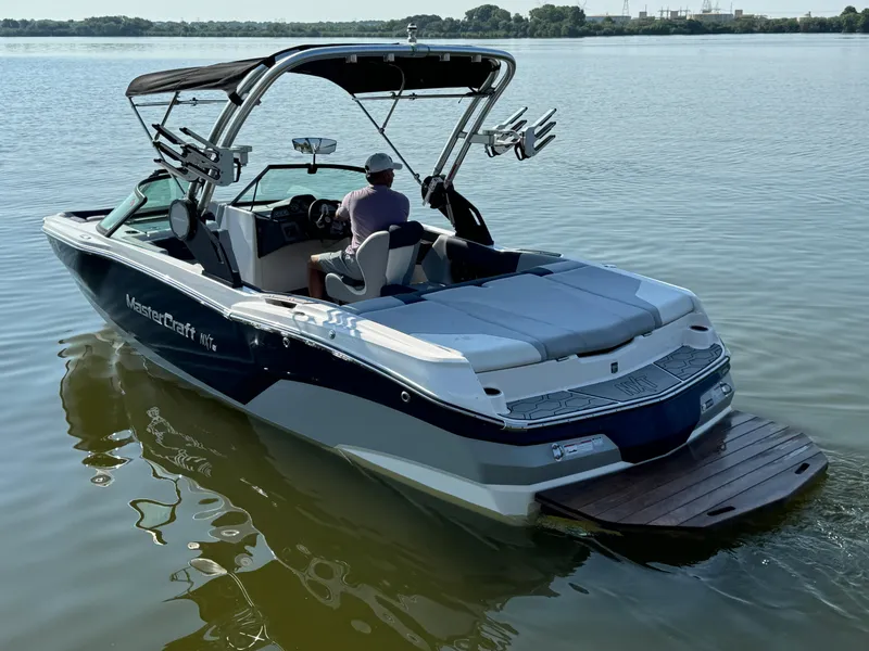 Slide: The Image of 2022 MasterCraft NXT20 boat on calm lake water, rear view. - 4