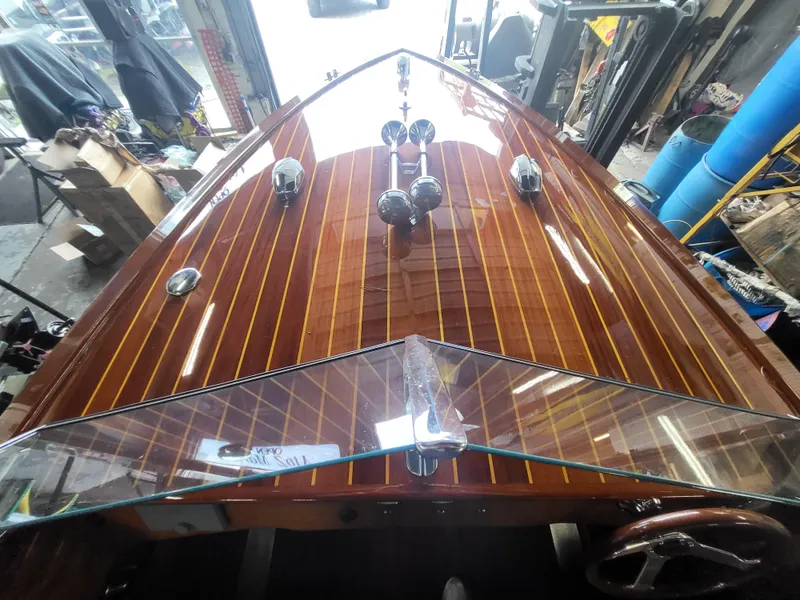 Slide: The Image of 2018 Cherubini Classic 24 boat with polished wooden deck and chrome accents in a workshop. - 10