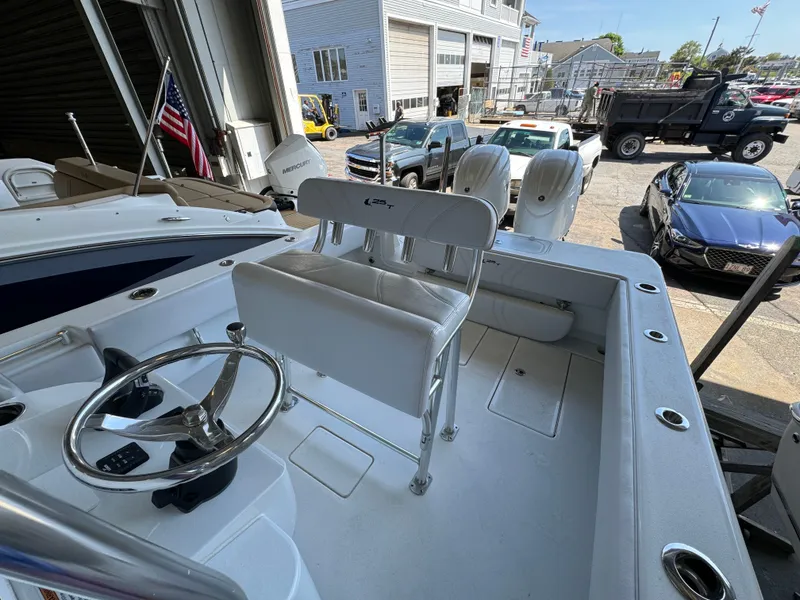 Slide: The Image of 2024 Contender 25 Tournament boat interior with steering wheel and seating, docked near vehicles. - 6