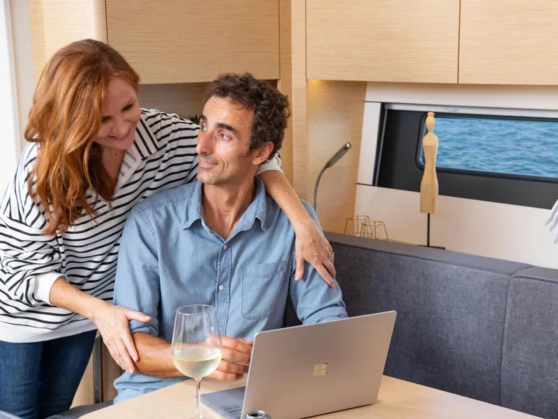 Slide: The Image of Couple enjoying time on a 2025 Hanse 510 yacht, with laptop and wine. - 18