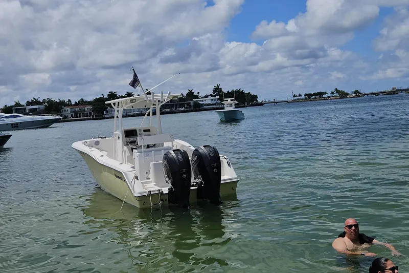 Slide: The Image of 2013 Tidewater 250 CC Adventure boat in calm waters, with people swimming nearby. - 2