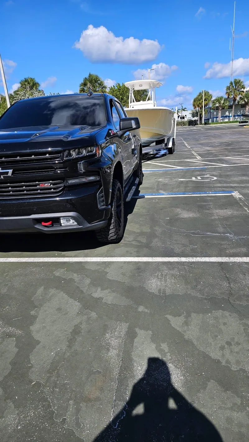 Slide: The Image of Black truck towing 2013 Tidewater 250 CC Adventure boat in parking lot. - 31