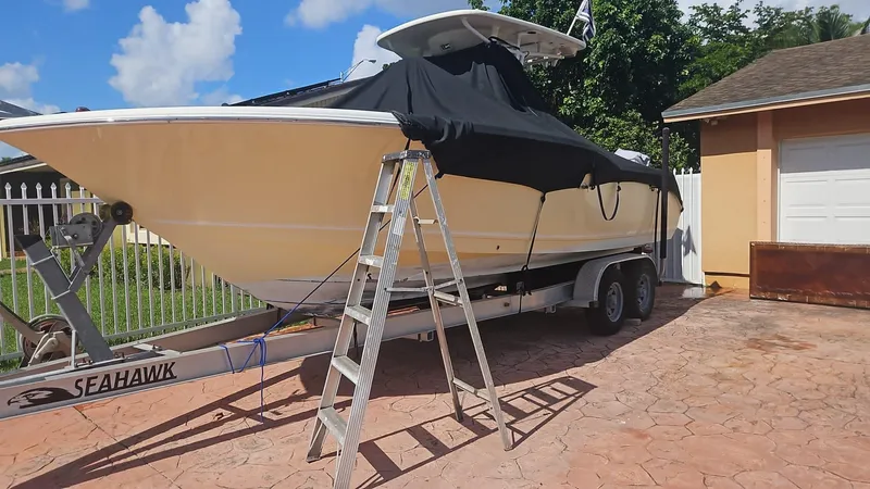 Slide: The Image of 2013 Tidewater 250 CC Adventure boat on trailer, covered, with ladder nearby. - 36