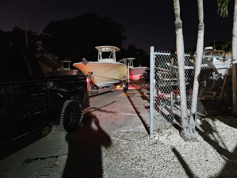 Slide: The Image of 2013 Tidewater 250 CC Adventure boat on trailer at night, near chain-link fence. - 48
