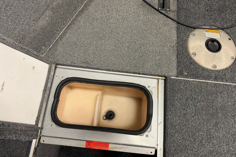 Slide: The Image of 2014 Alumacraft Voyageur 175 Tiller boat interior with storage compartment and carpeted floor. - 13