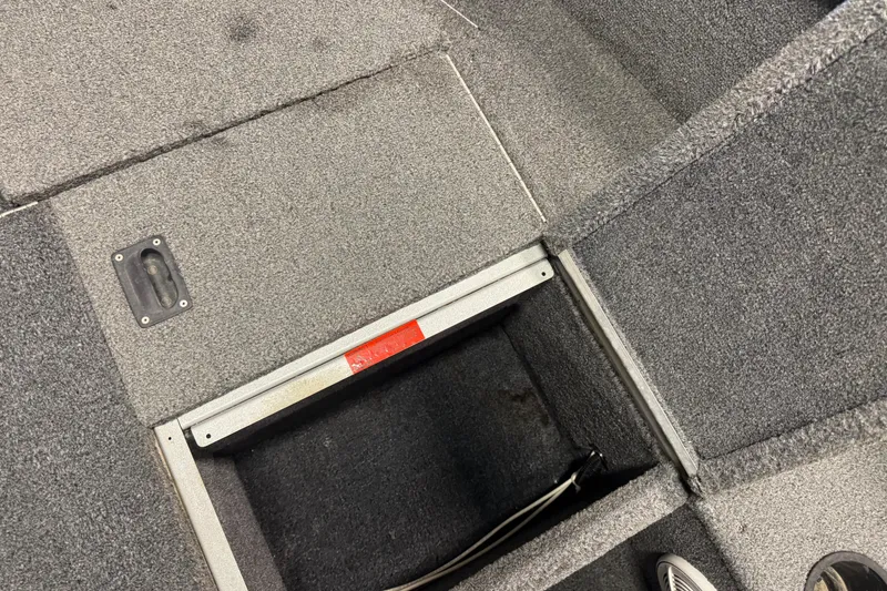 Slide: The Image of 2014 Alumacraft Voyageur 175 Tiller boat storage compartment with gray carpeted interior. - 14