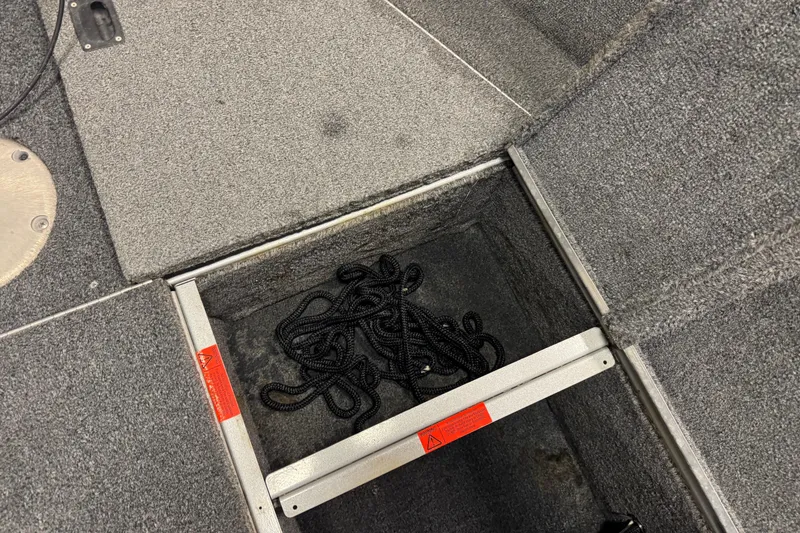 Slide: The Image of 2014 Alumacraft Voyageur 175 Tiller storage compartment with coiled black rope. - 15