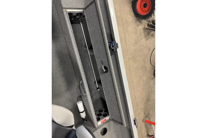 Slide: The Image of 2014 Alumacraft Voyageur 175 Tiller interior storage compartment with rod holders. - 18