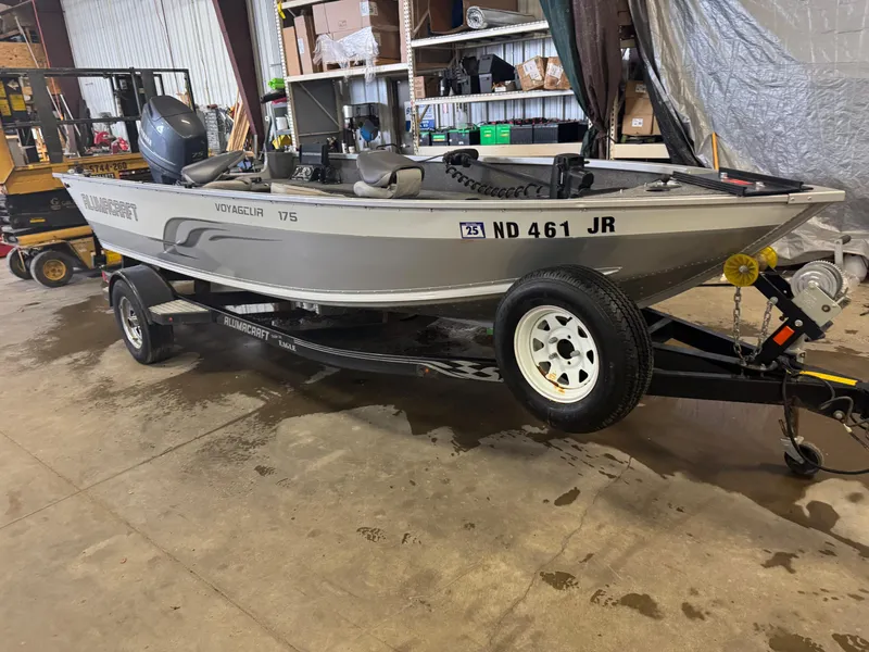 Slide: The Image of 2014 Alumacraft Voyageur 175 Tiller boat on trailer in indoor storage. - 2