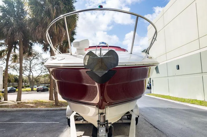 The Image of 2007 Monterey 250 Cruiser boat, red hull, parked outdoors near palm trees. - 1
