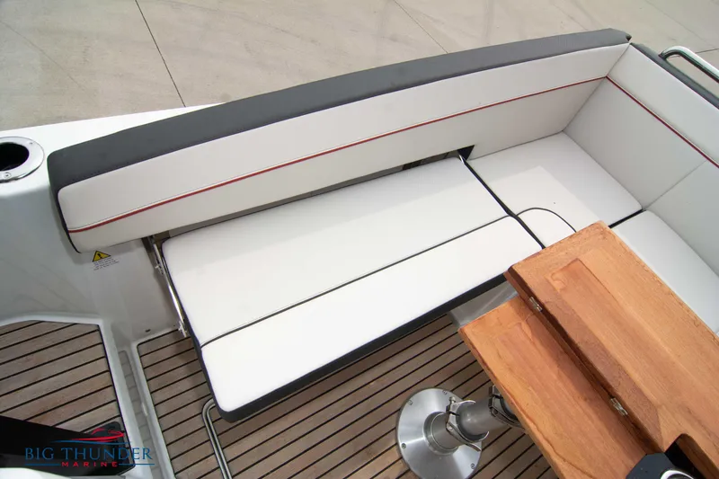 Slide: The Image of 2024 Jeanneau Leader 9.0 WA boat seating area with wooden table and cushioned bench. - 19