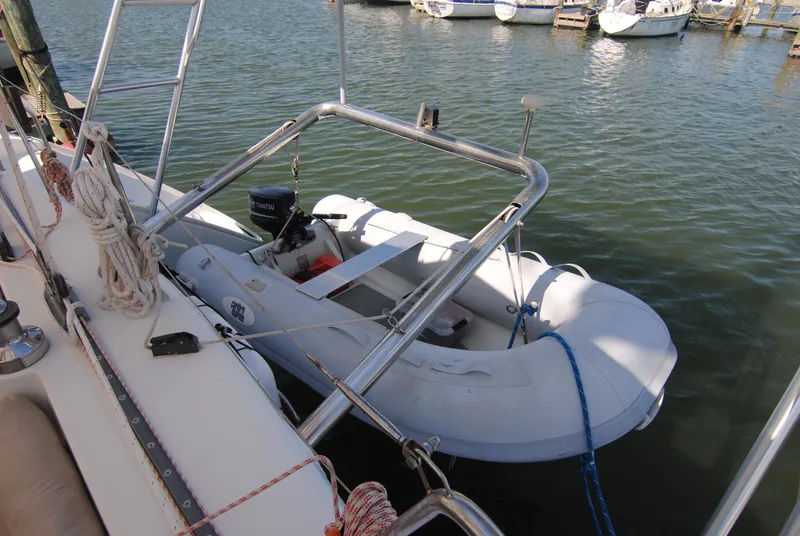 Slide: The Image of Inflatable dinghy attached to 1999 Lagoon 410 catamaran, docked at marina. - 14