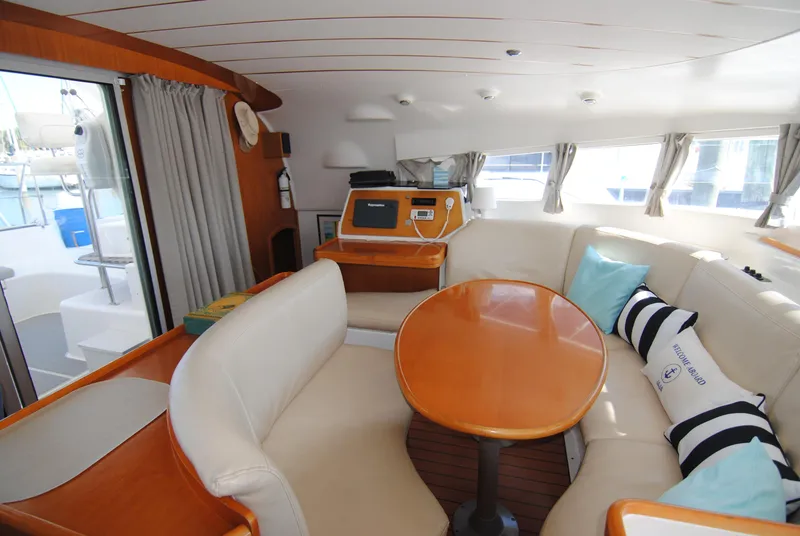 Slide: The Image of Interior of 1999 Lagoon 410 catamaran with cozy seating and wooden table. - 20