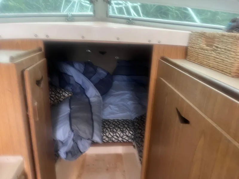 Slide: The Image of 1973 Bertram 28 Flybridge Cruiser cabin interior with cozy bedding and wooden cabinetry. - 10