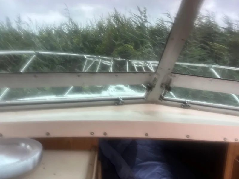 Slide: The Image of Interior view of 1973 Bertram 28 Flybridge Cruiser with lush greenery outside. - 14