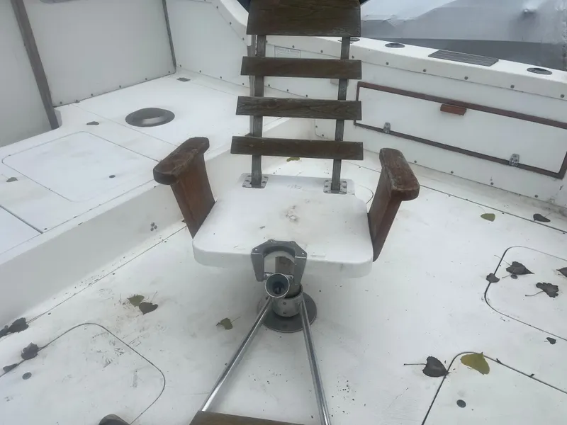 Slide: The Image of 1973 Bertram 28 Flybridge Cruiser deck with fishing chair and scattered leaves. - 16