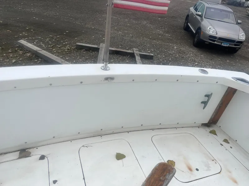 Slide: The Image of 1973 Bertram 28 Flybridge Cruiser deck with American flag and parked car in background. - 17