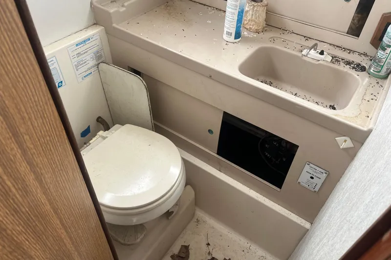Slide: The Image of 1973 Bertram 28 Flybridge Cruiser bathroom with toilet and sink, showing signs of wear. - 40
