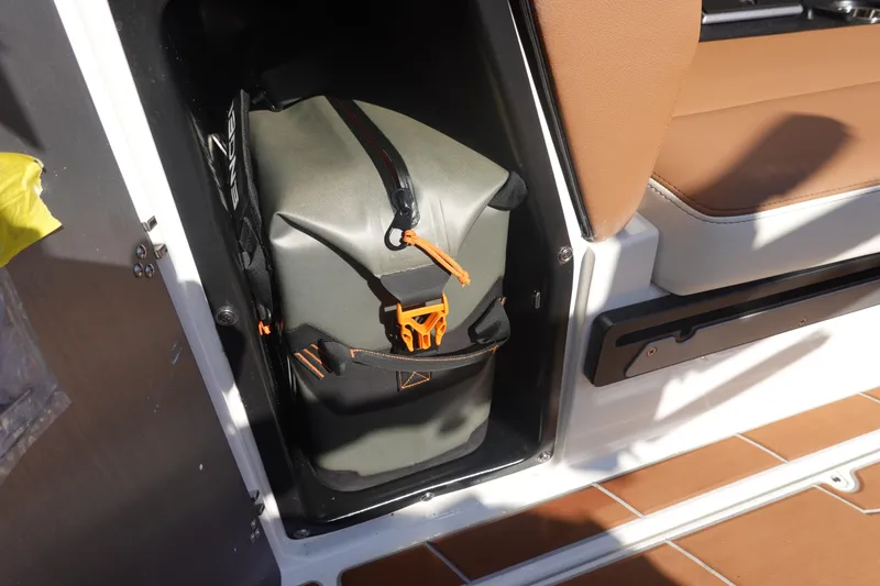 Slide: The Image of Storage compartment in 2025 Malibu Wakesetter 25 LSV with a secured bag. - 24