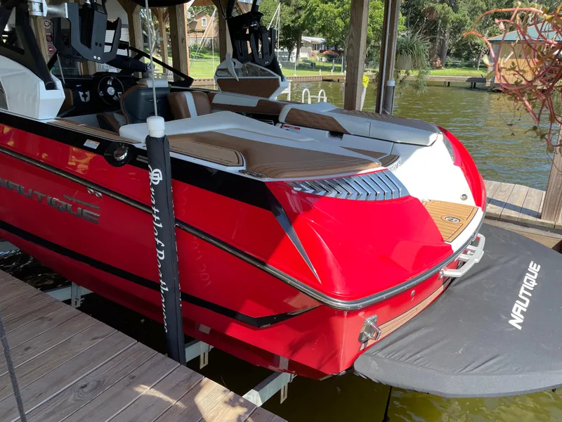 Slide: The Image of 2019 Nautique Super Air Nautique G23 Coastal Edition in vibrant red docked by the water. - 12