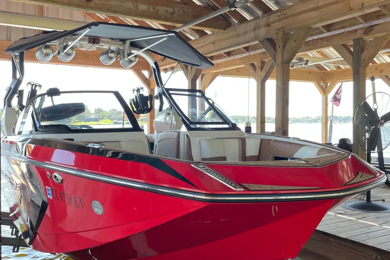 Slide: The Image of 2019 Nautique Super Air Nautique G23 Coastal Edition in red, docked under a wooden shelter. - 13
